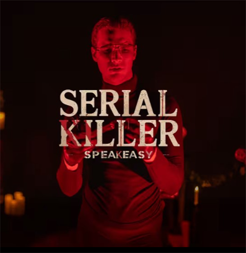 A dark, red-lit promotional image showing a person standing and holding an object at chest level, illuminated dramatically by candlelight. Overlaid text reads “Serial Killer Speakeasy,”